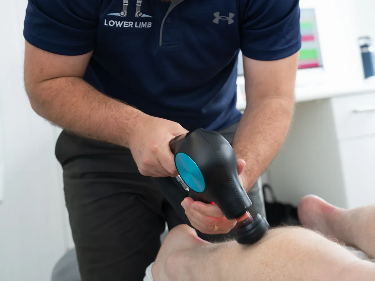 Hands-on soft tissue treatment with percussion therapy at Lower Limb Clinic Belfast